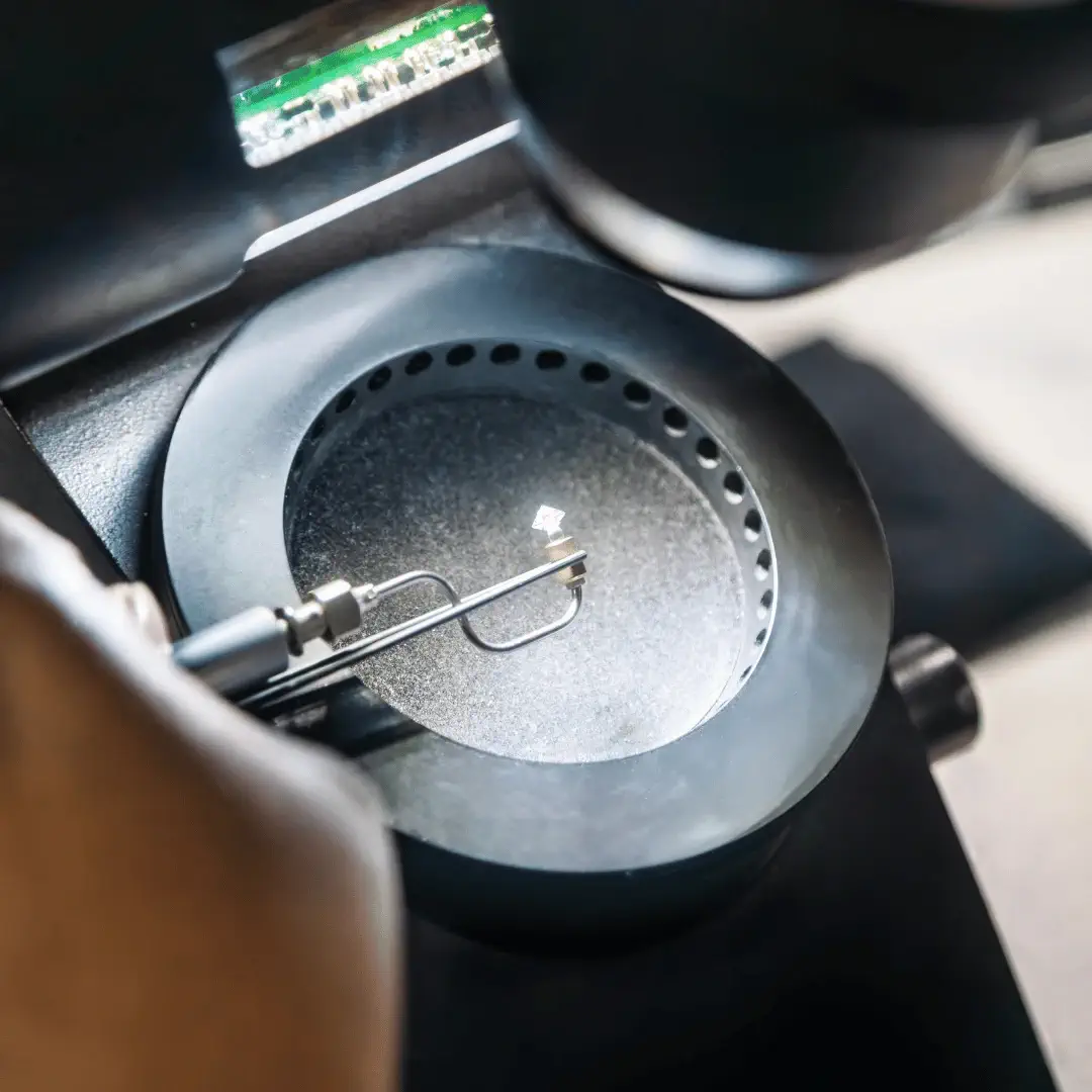 Jeweler inspecting a round brilliant diamond with a loupe to grade the 4Cs